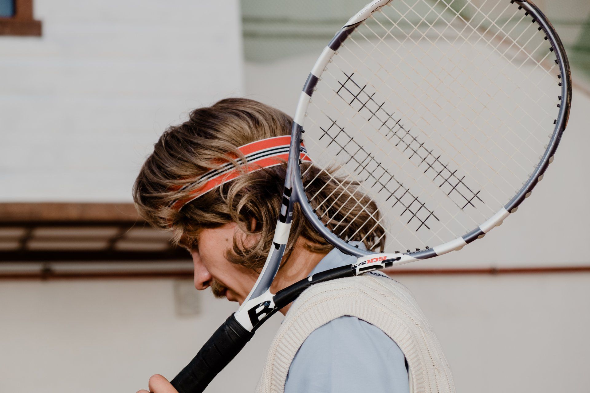 Un hombre sostiene una raqueta de tenis sobre su hombro.