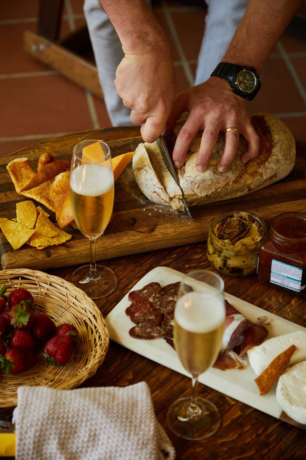 A man is cutting a loaf of bread on a cutting board.