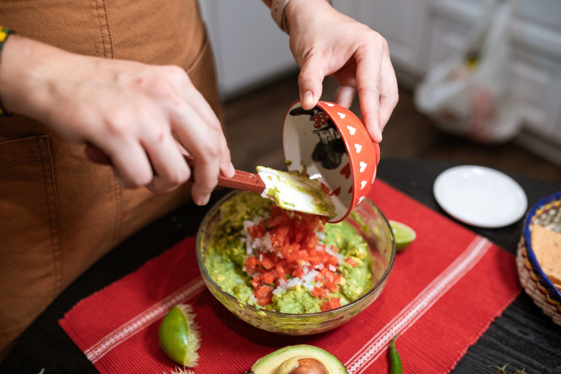 A person is making guacamole in a bowl with a spoon.