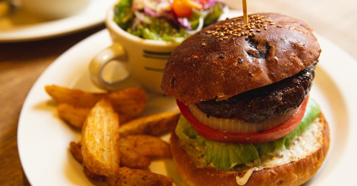A hamburger and french fries on a white plate on a table.