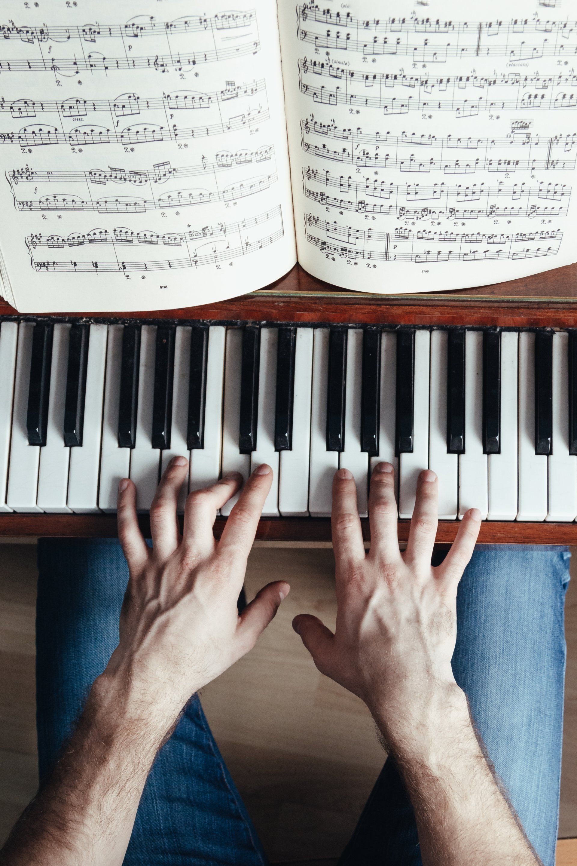A person is playing a piano with their hands on the keys.