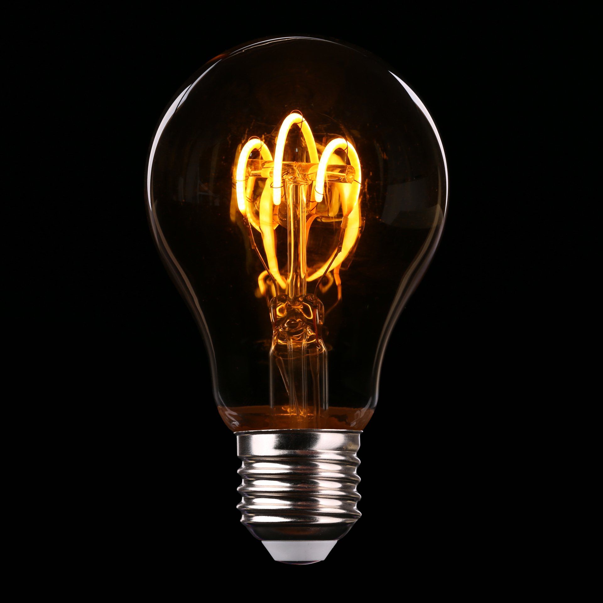 A picture of an illuminated lightbulb on a black background.