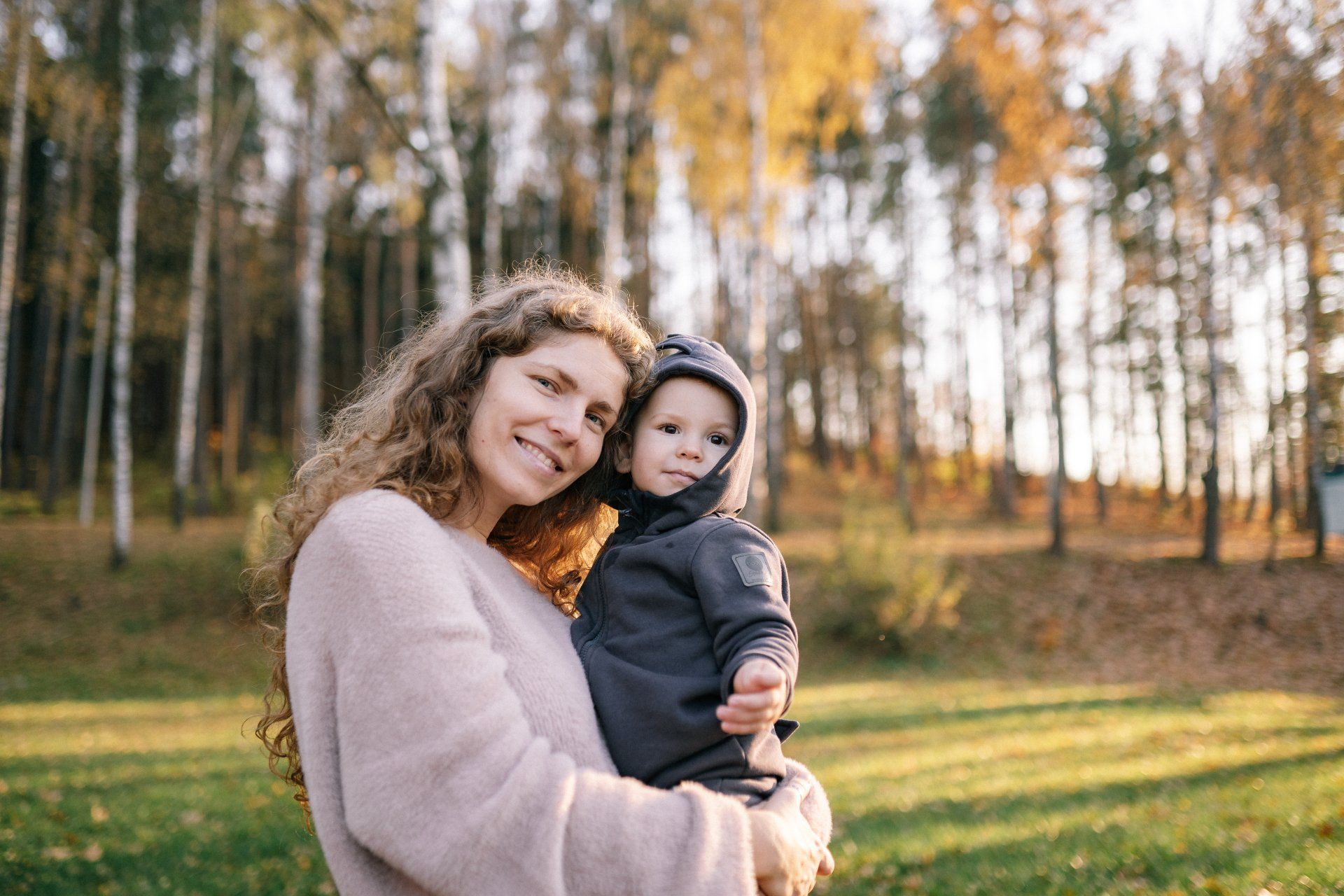 A woman is holding a baby in her arms in a park.