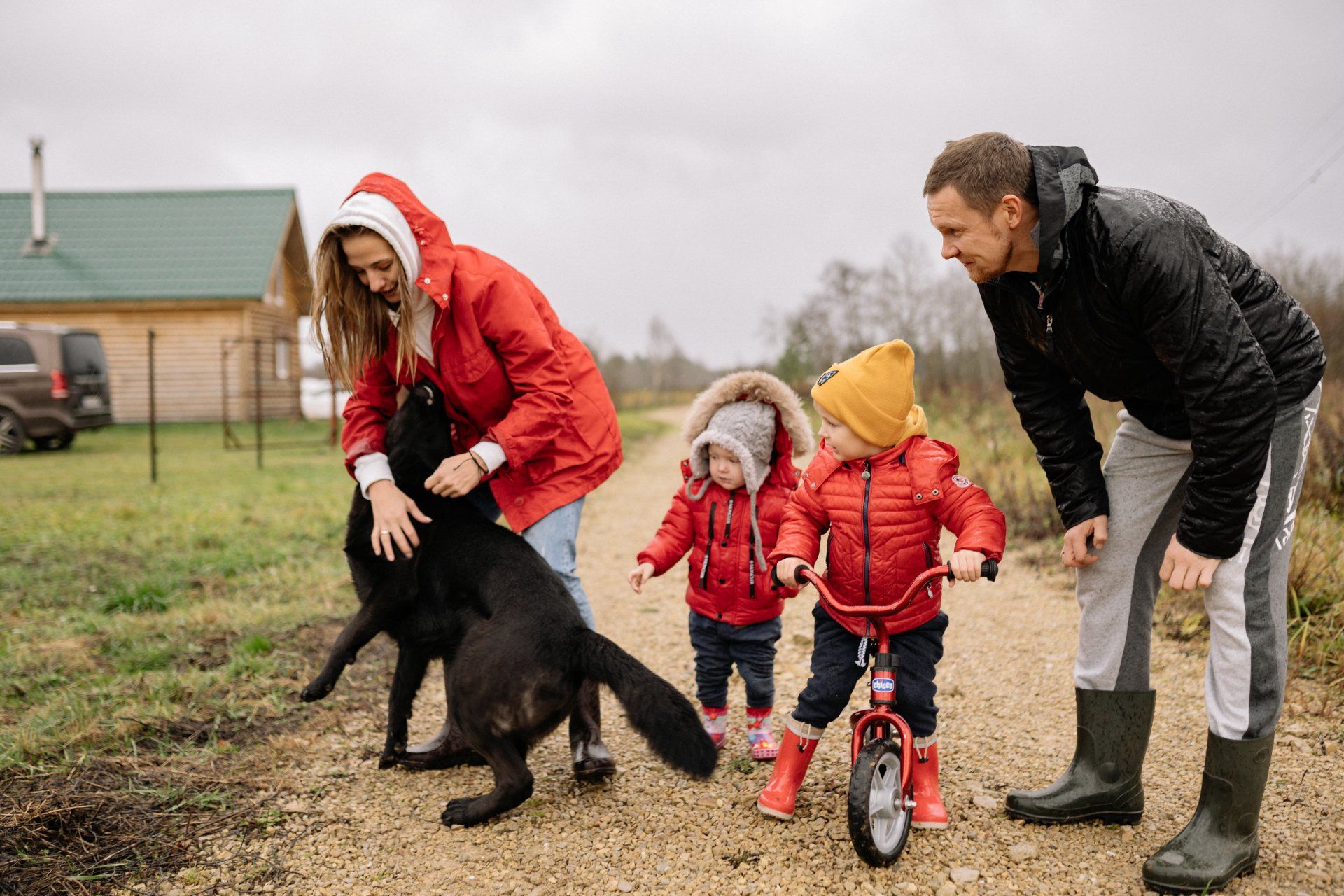 a family is walking a dog and two children are riding a bike .