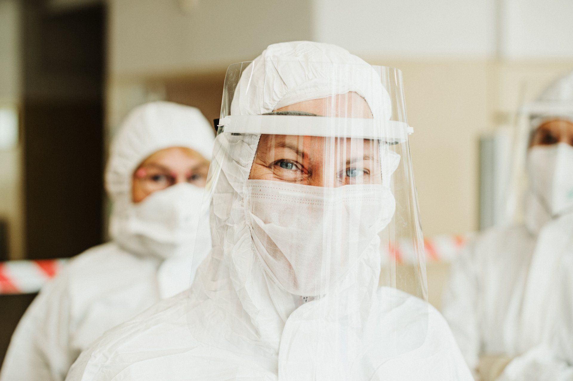 A group of people wearing protective suits and face shields.
