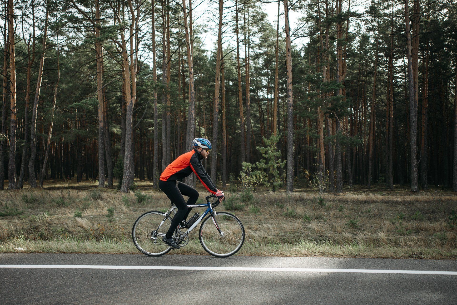 A man is riding a bike on a road in the woods.