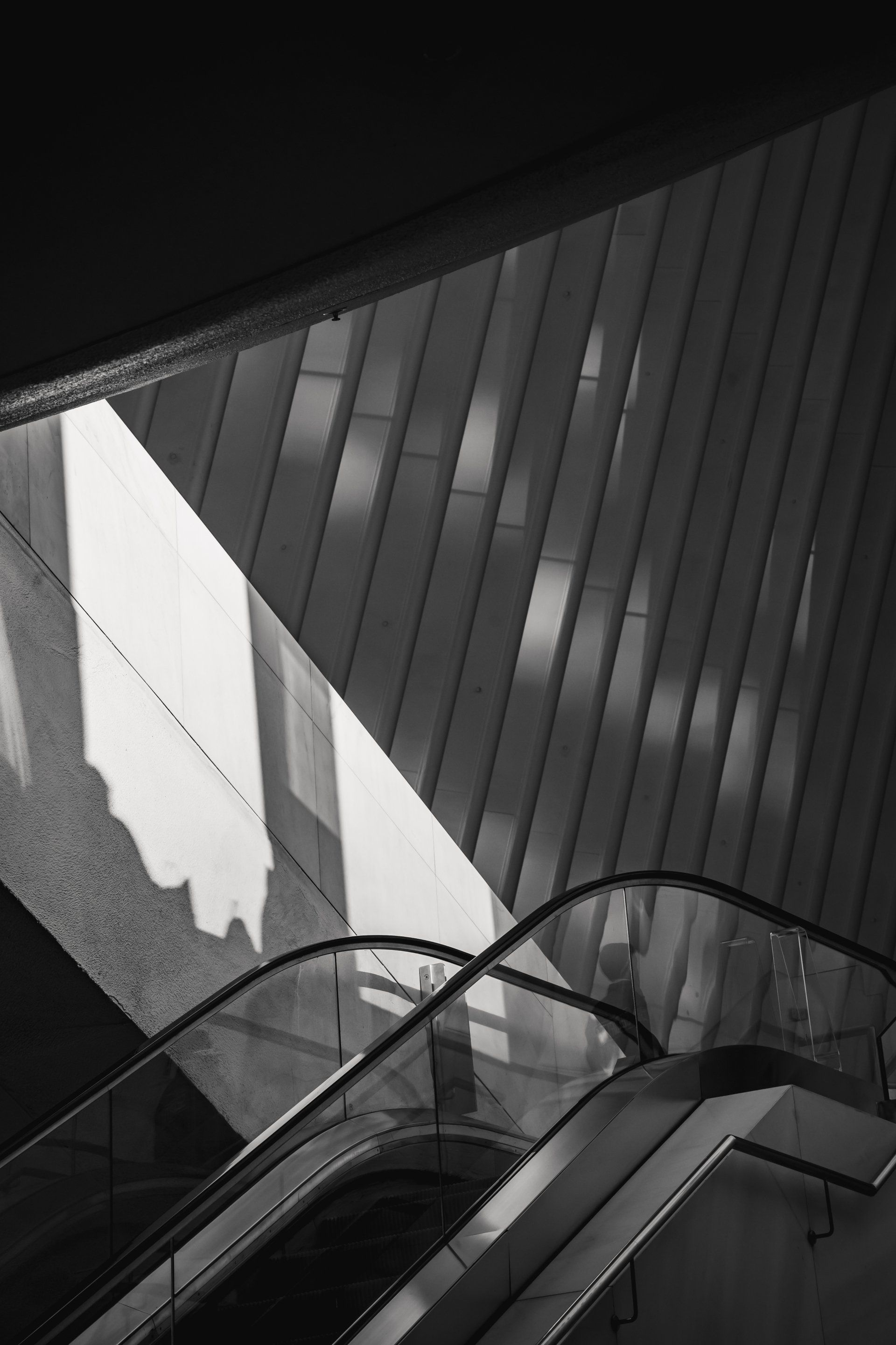 A black and white photo of an escalator in a building