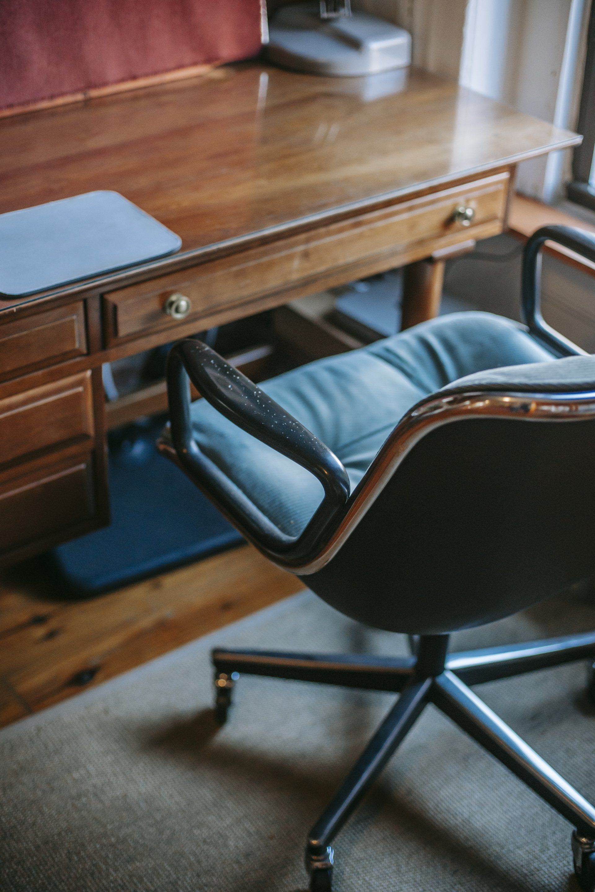 An office chair is sitting in front of a wooden desk