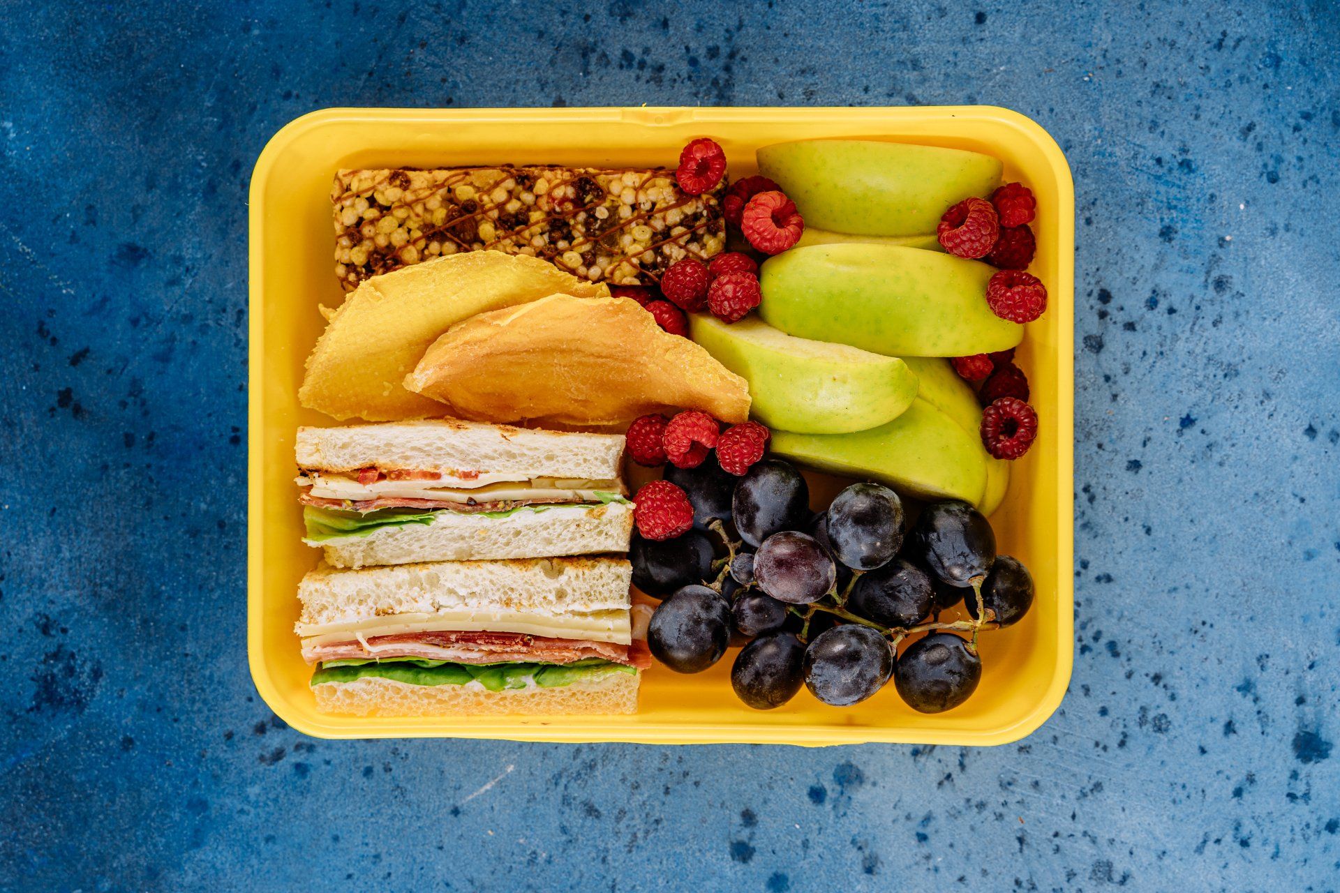 Gele lunchbox gevuld met gezonde ingrediënten 