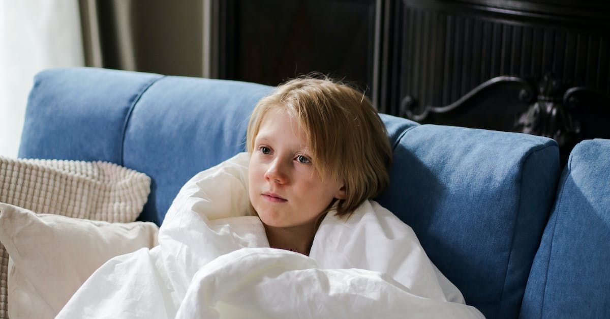 a young boy wrapped in a white blanket is sitting on a blue couch