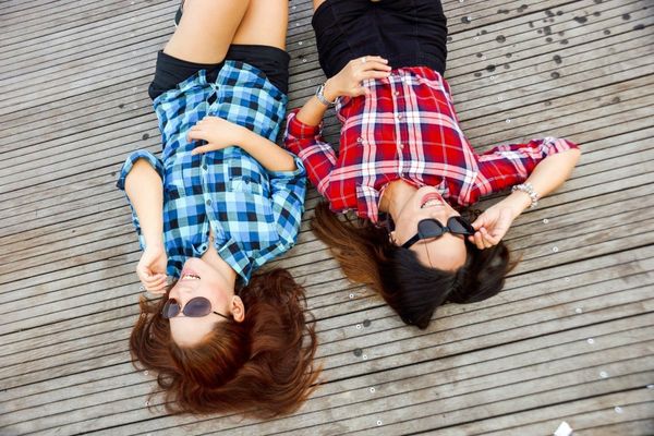 Two women are laying next to each other on a wooden floor.