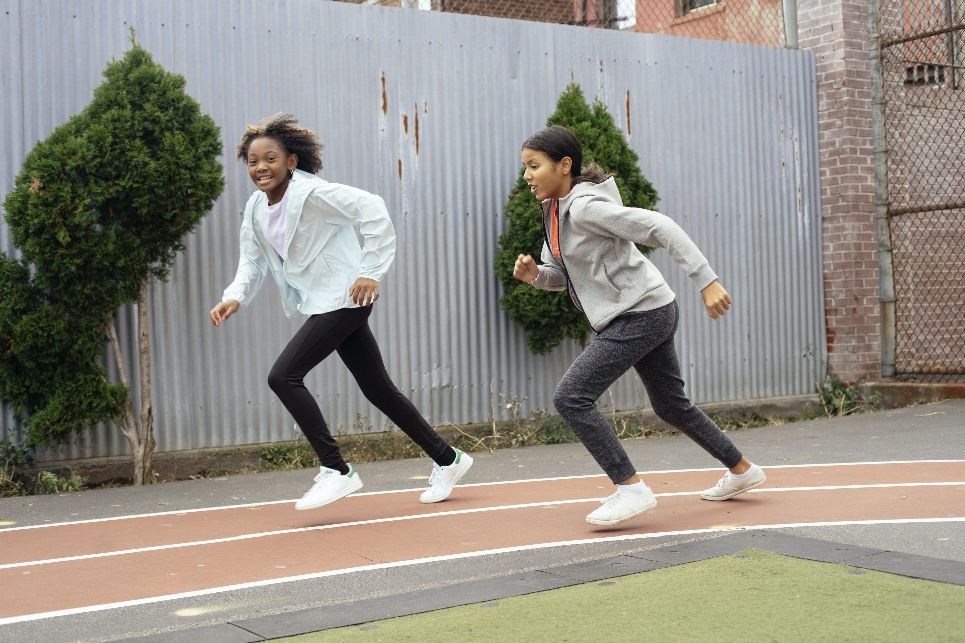 two young girls are running on a track.