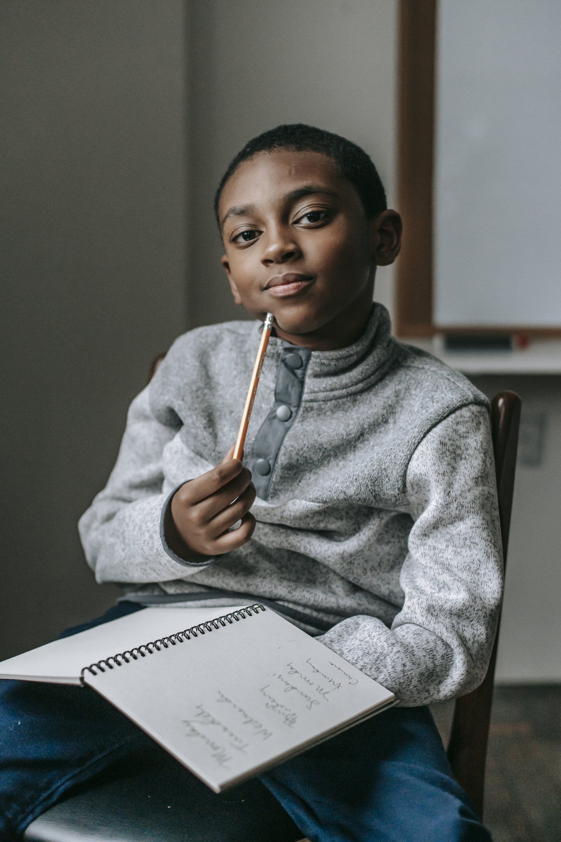 Eastchester Church of God. young boy is sitting in a chair holding a pencil and a notebook.