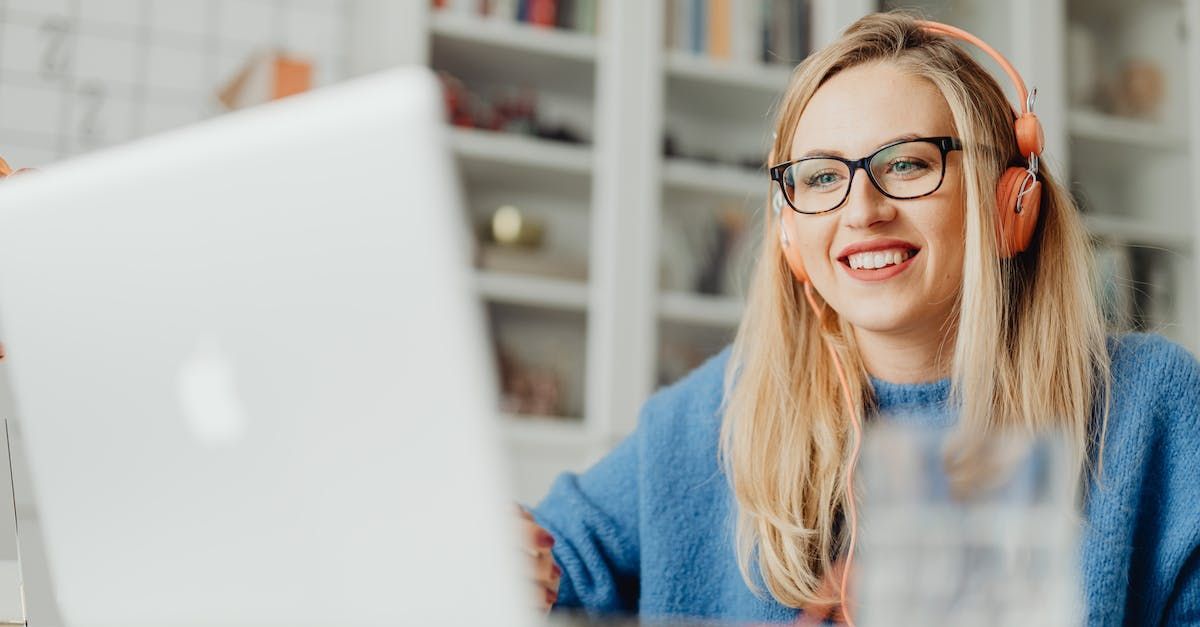 A woman wearing headphones and glasses is sitting in front of a laptop computer.