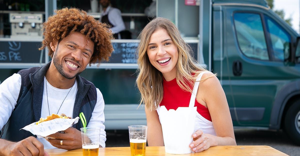 a man and a woman are sitting at a table in front of a food truck