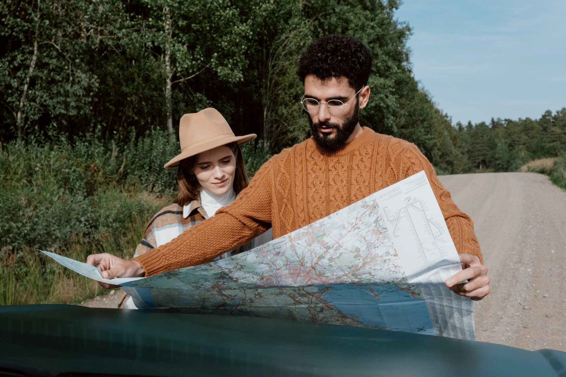 man and woman reading a map on the side of the road