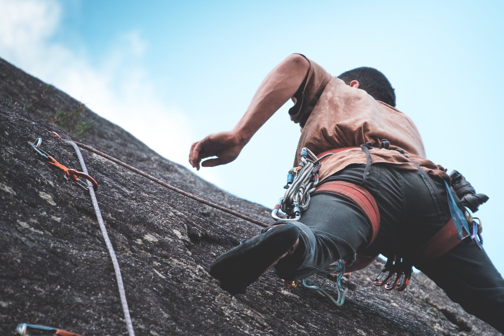 A man is climbing up a rock wall with a rope.