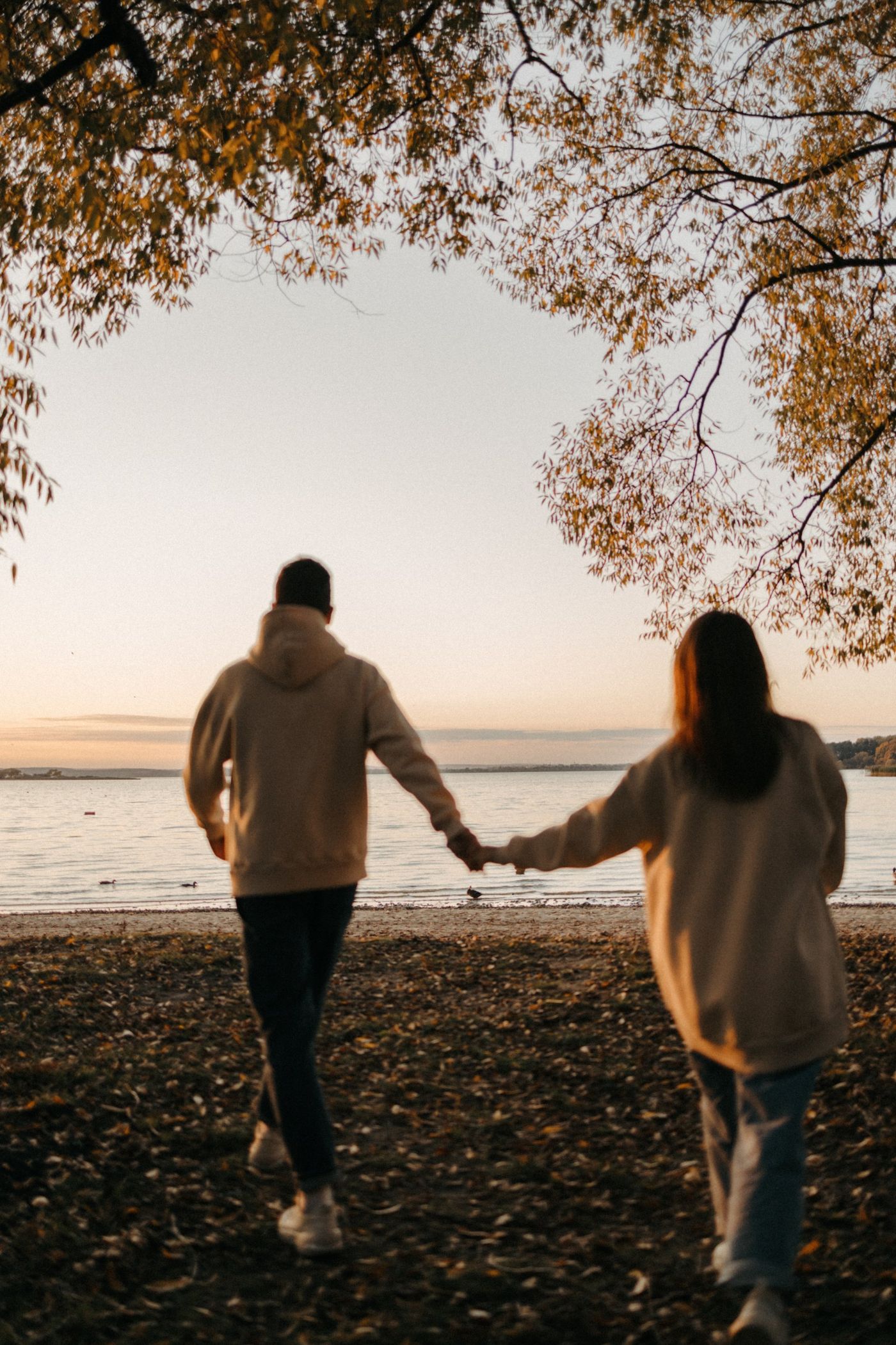 A man and a woman are holding hands while walking on a beach.