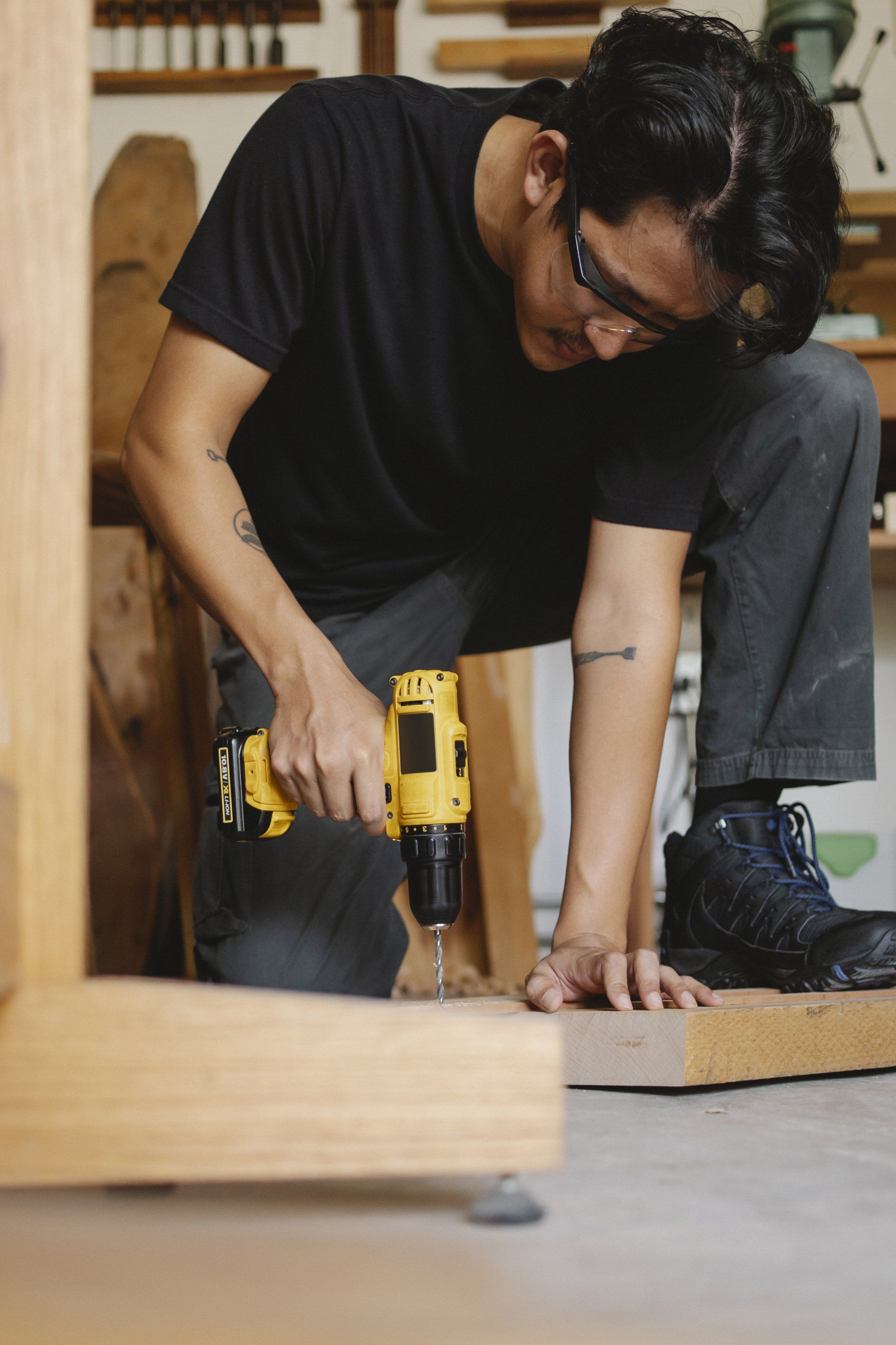 A man is using a drill to drill a hole in a piece of wood.