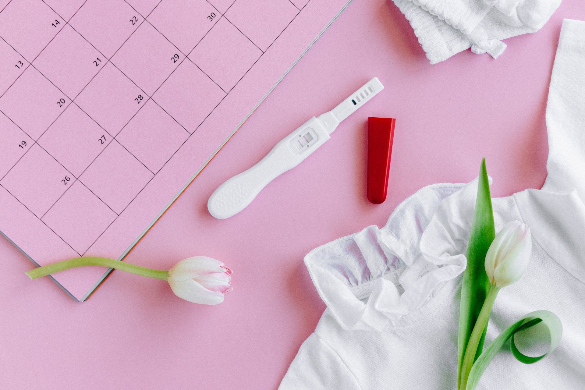 pregnancy test next to a calendar with a white shirt