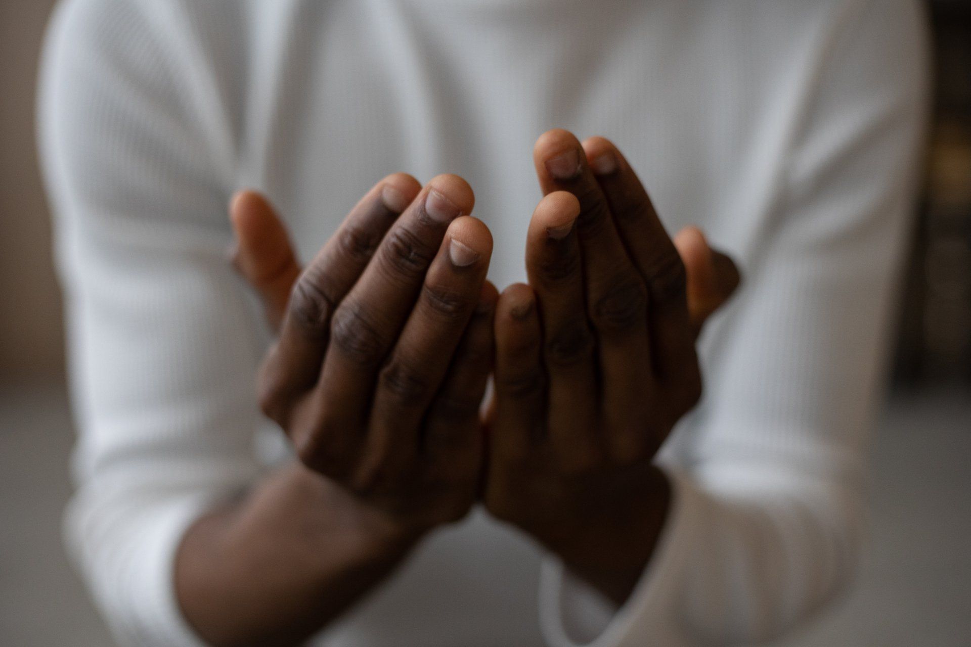 A man in a white shirt is praying with his hands together.