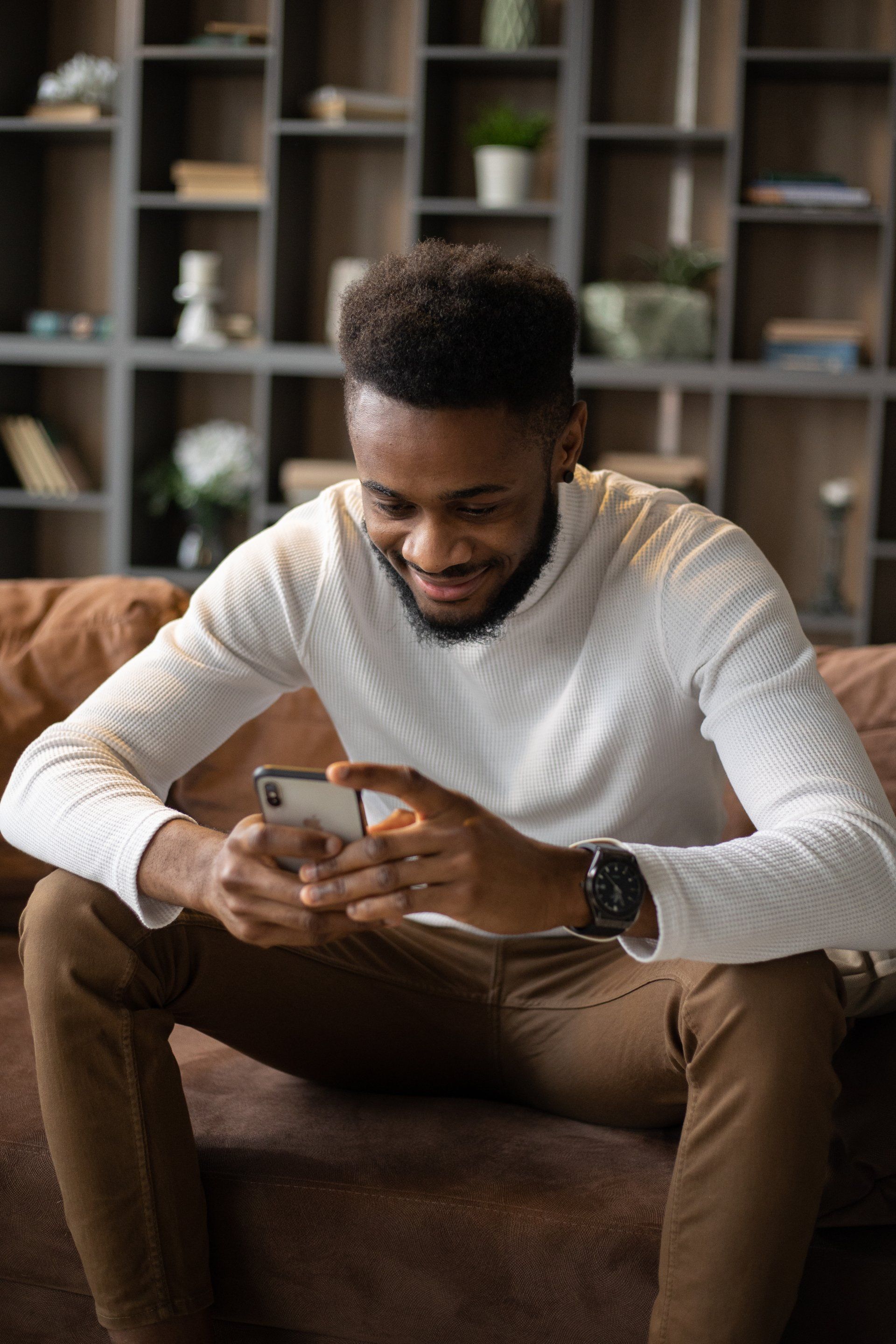 A man is sitting on a couch looking at his cell phone.