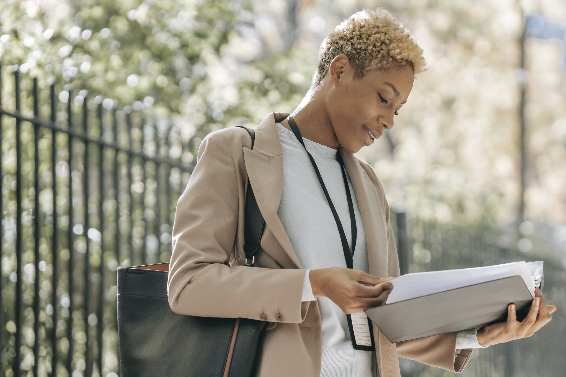 A woman in a suit is holding a folder and looking at it.