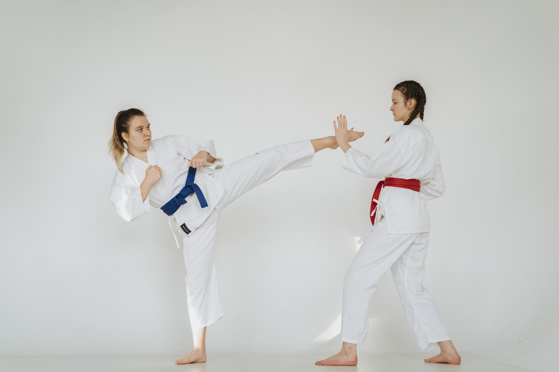 Two women are practicing karate together in a gym.