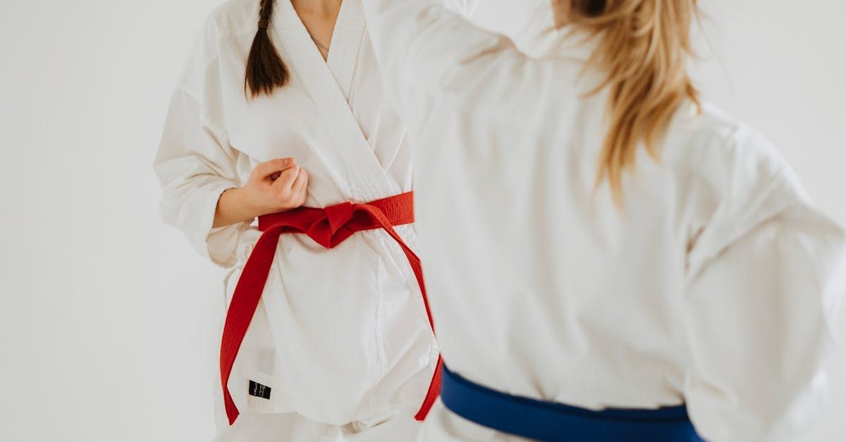 two women in white karate uniforms with red and blue belts
