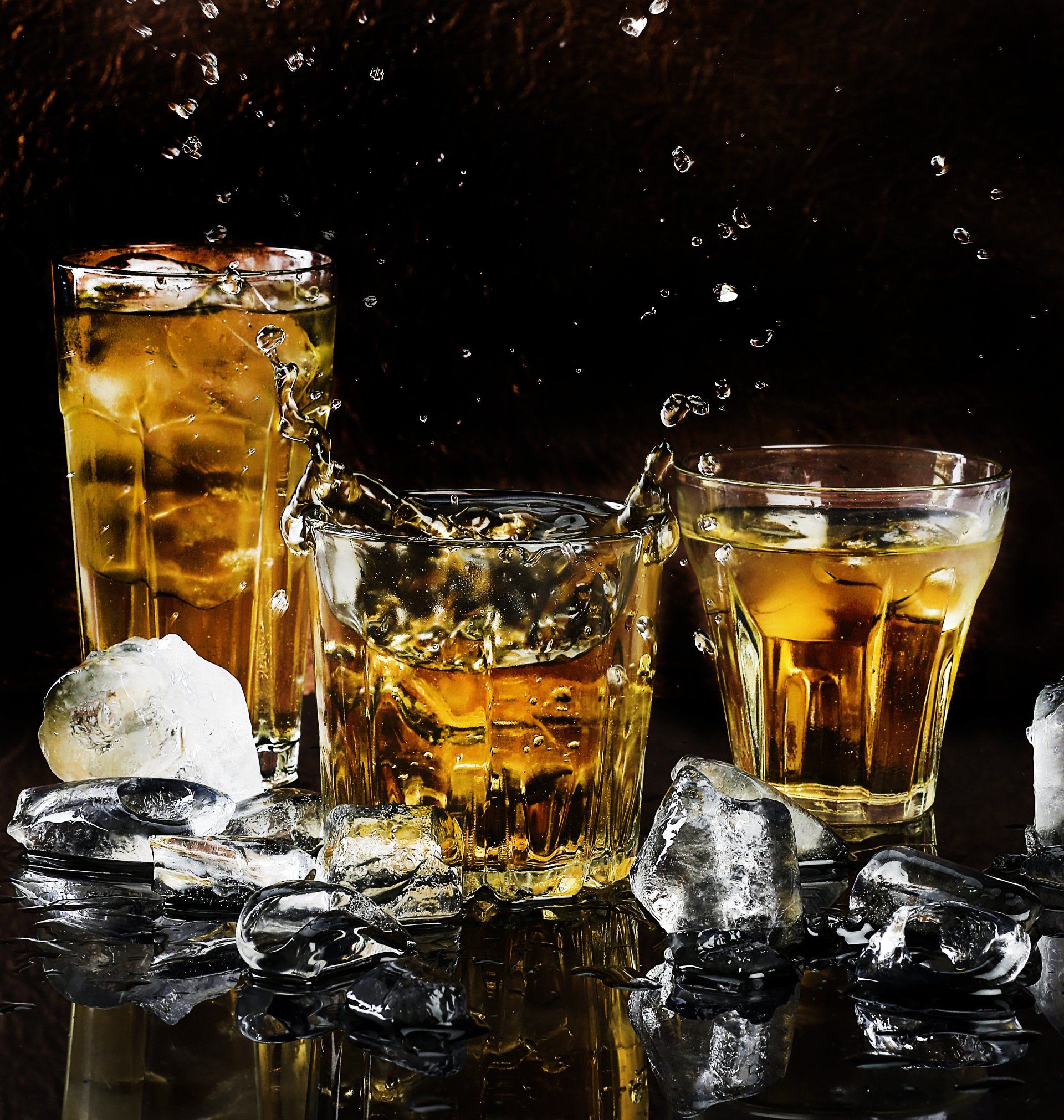 Three glasses of whiskey with ice on a table