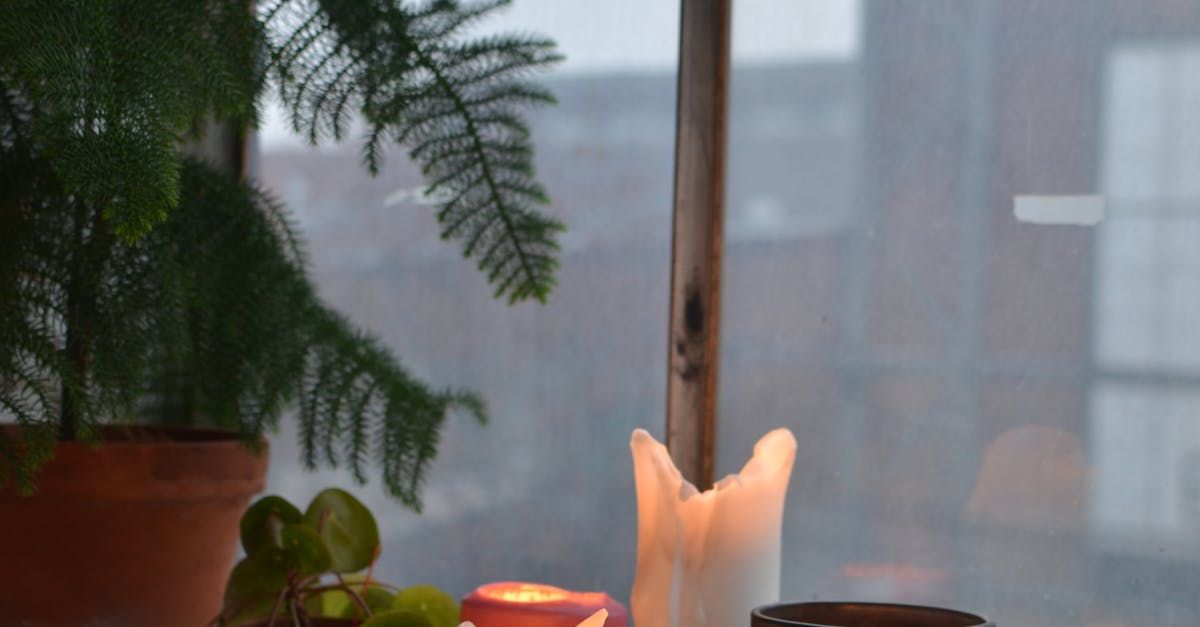 A candle is lit on a table in front of a window.