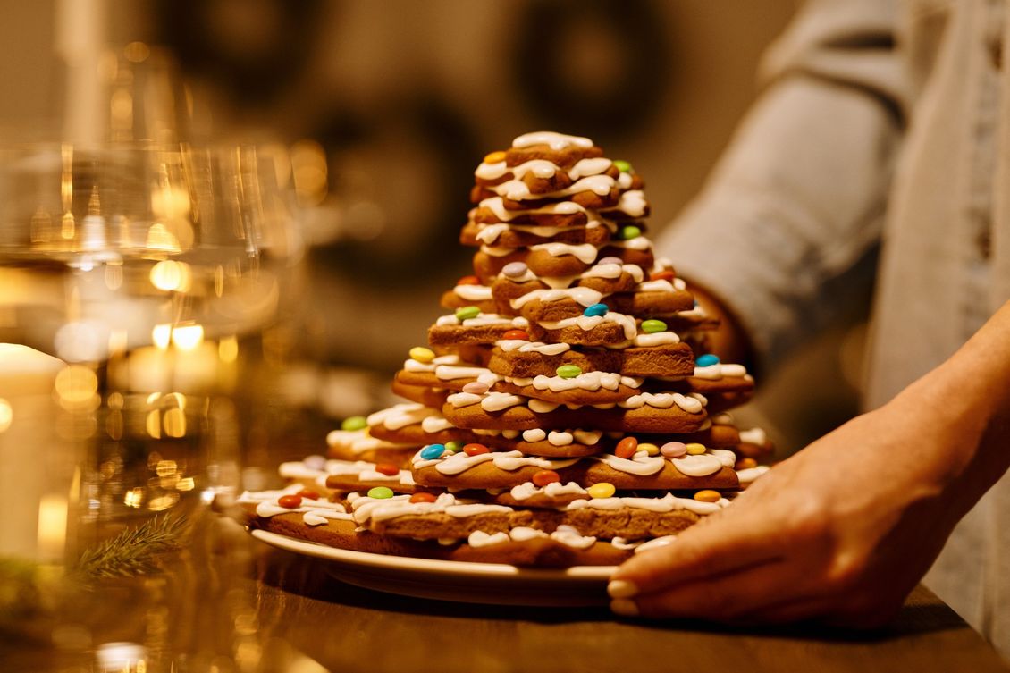 A person is holding a plate of gingerbread cookies in the shape of a christmas tree.