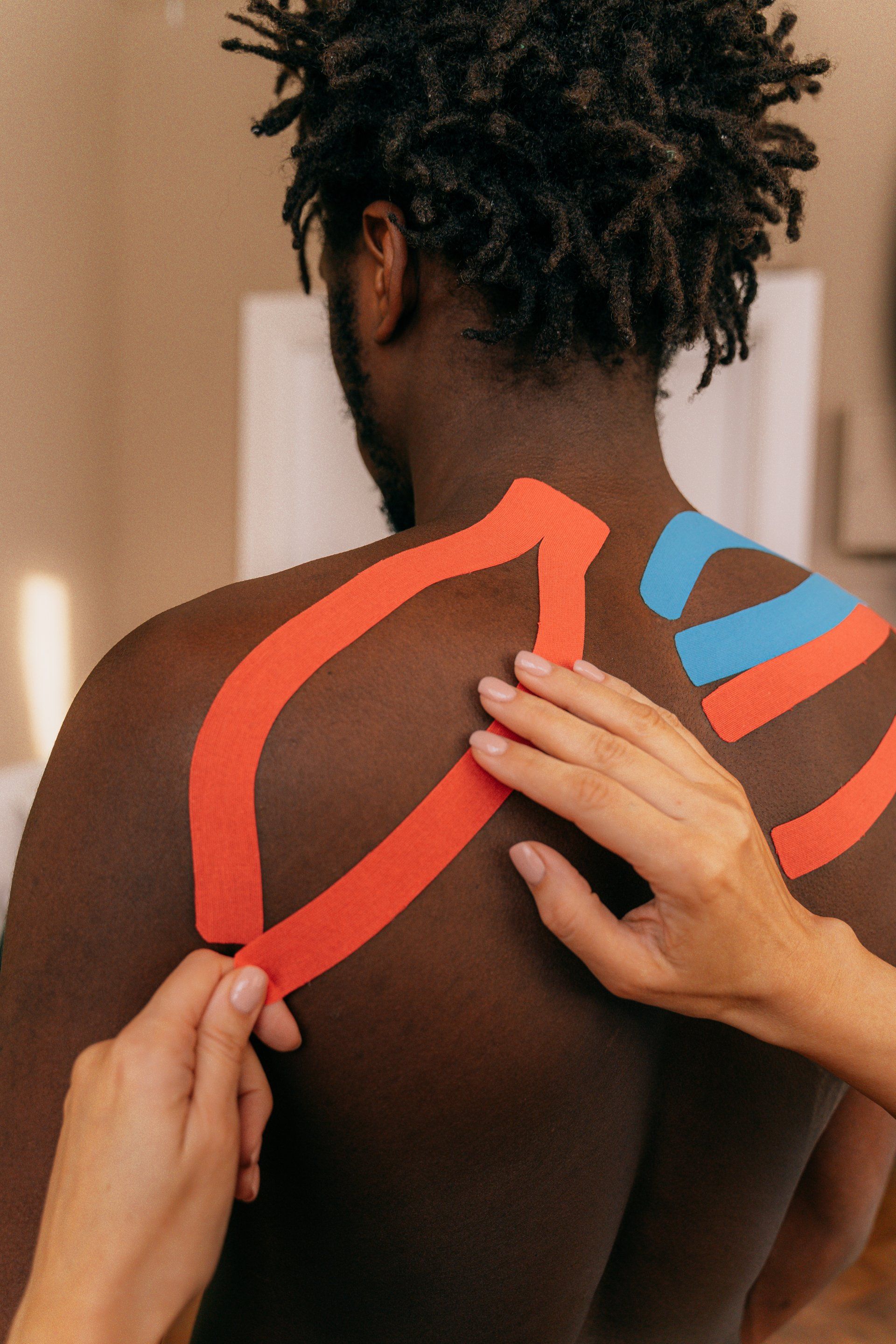 A person is putting kinesio tape on a man 's back.