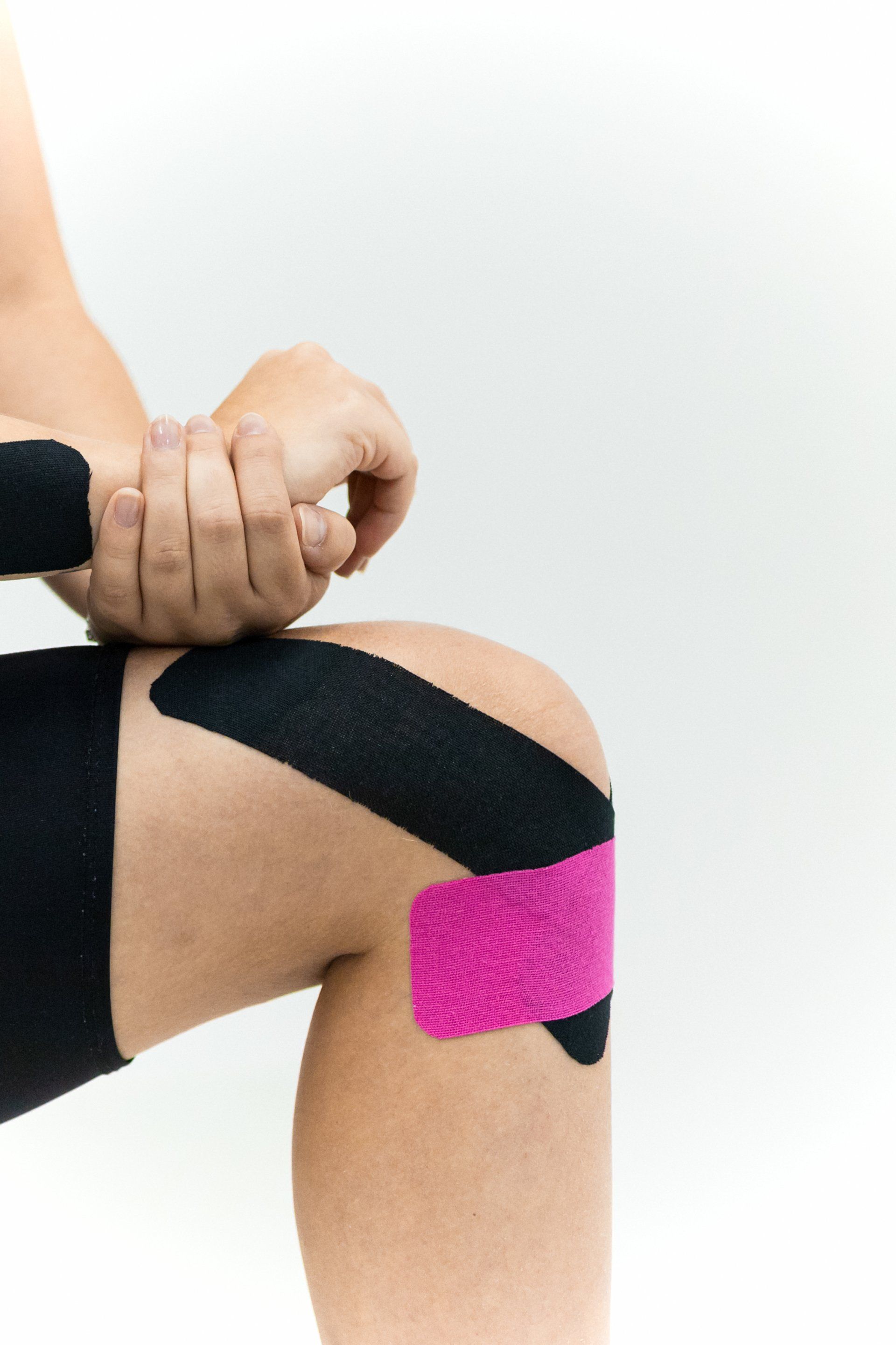 A person is applying kinesio tape to their knee.