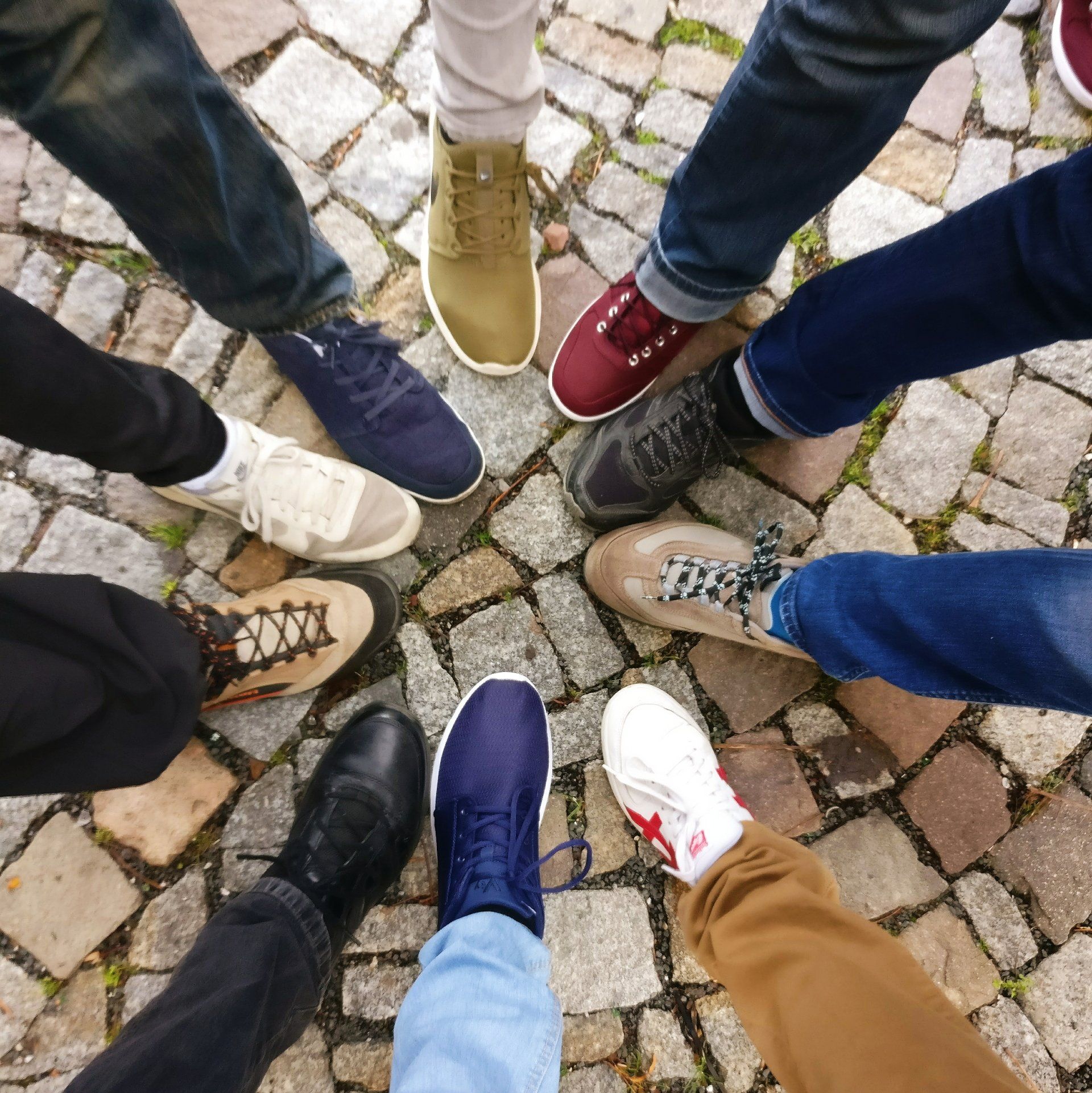 A group of people standing in a circle wearing different shoes