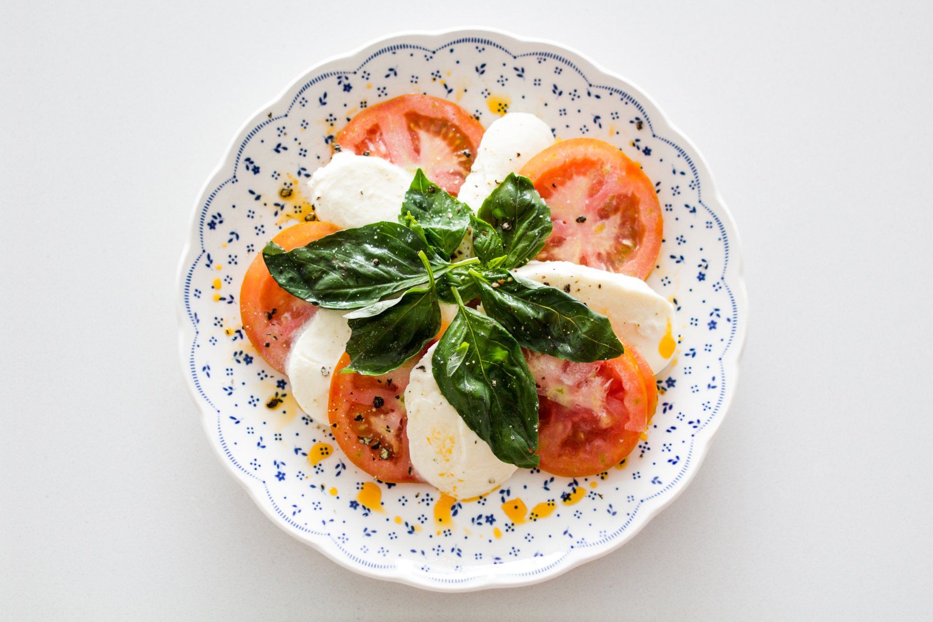 A white plate topped with tomatoes , mozzarella and basil.