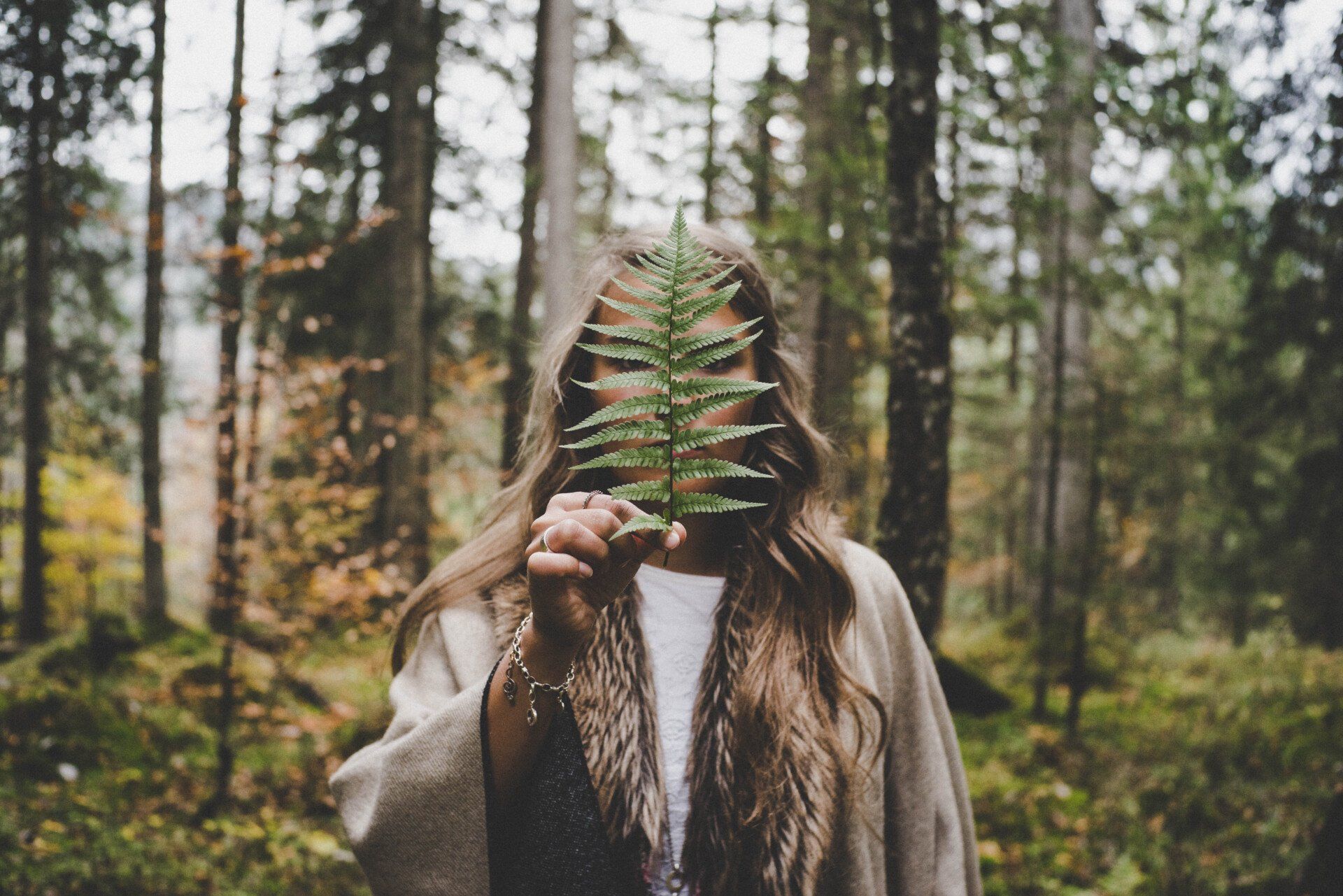 Natuurlijker energie boosters, vrouw in het bos met blad voor haar gezicht