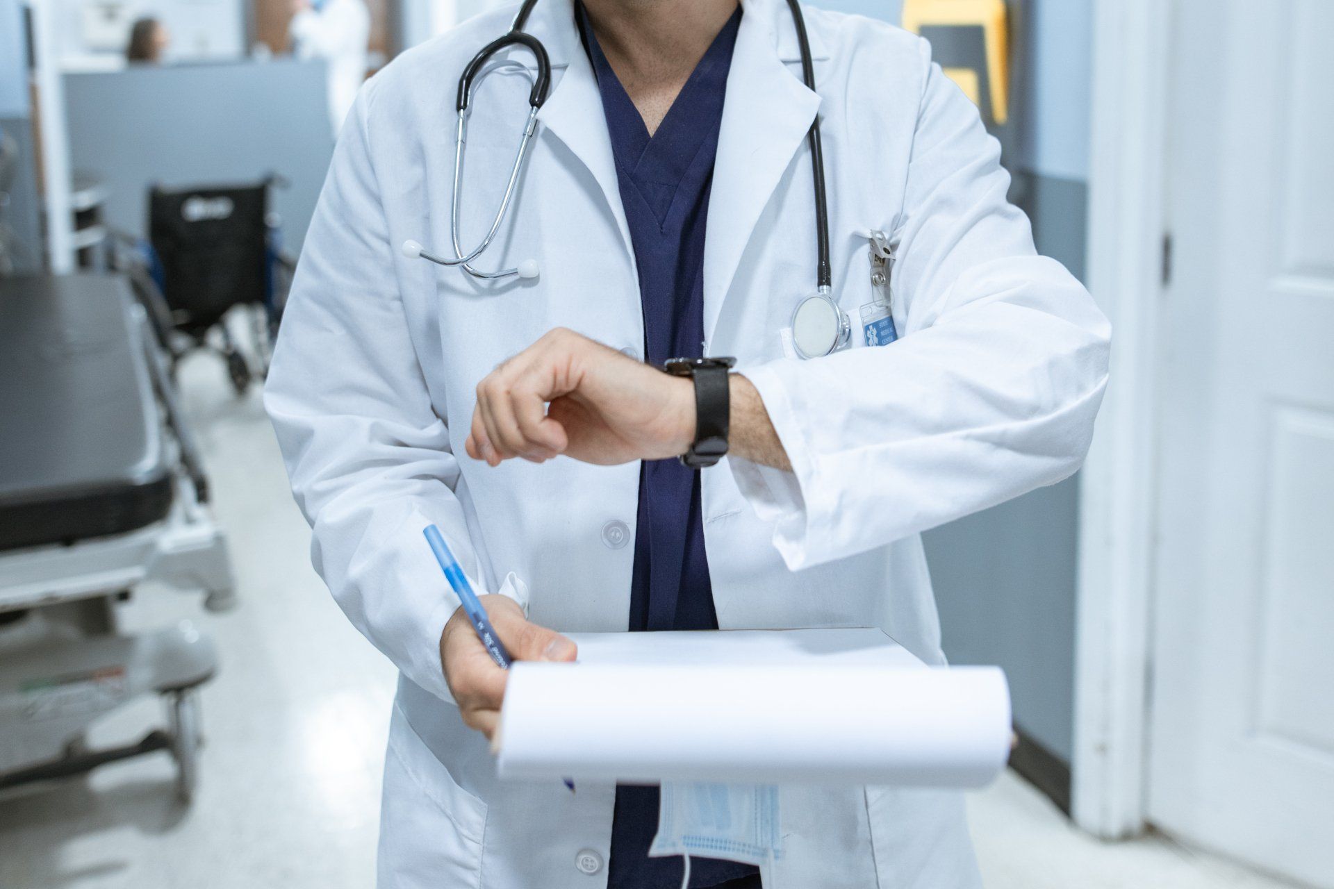 Doctor Checking Watch and Holding Clipboard in Hospital Hallway