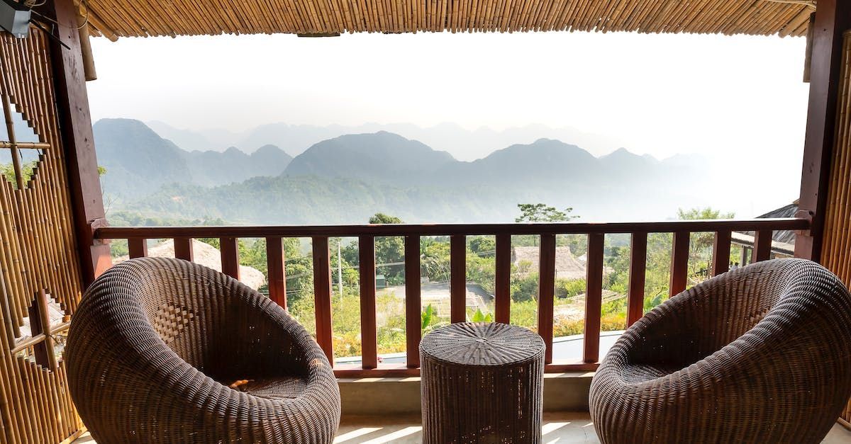 Two chairs and a table on a balcony with mountains in the background