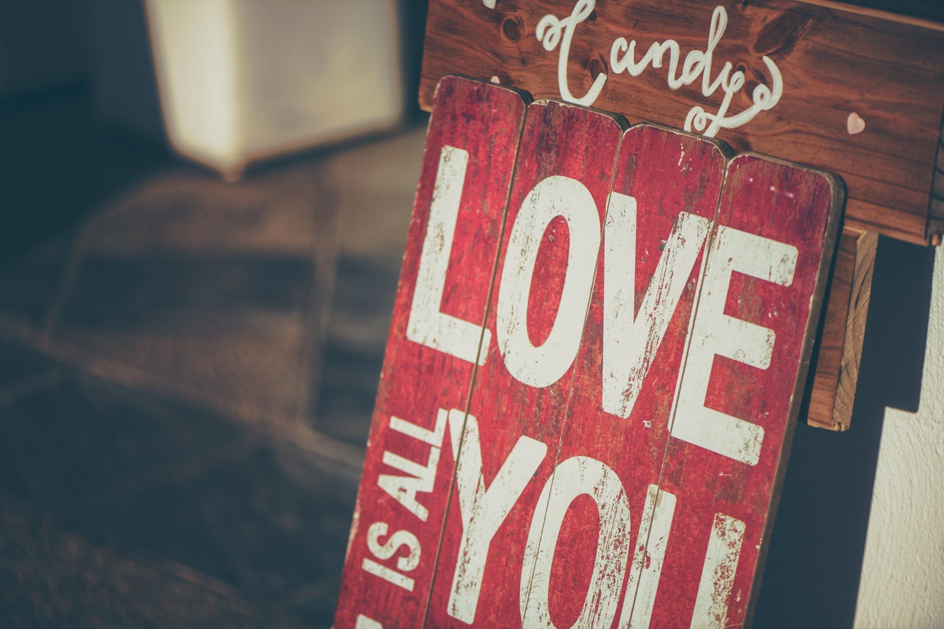 a wooden sign that says `` love is all you '' is hanging on a wall .