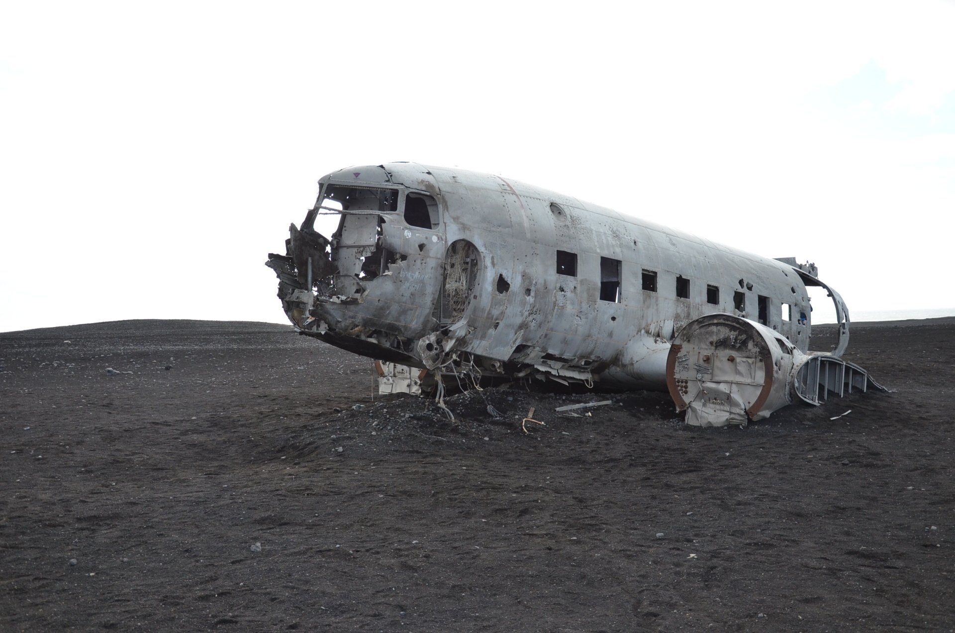 A wrecked airplane is sitting on top of a dirt field.