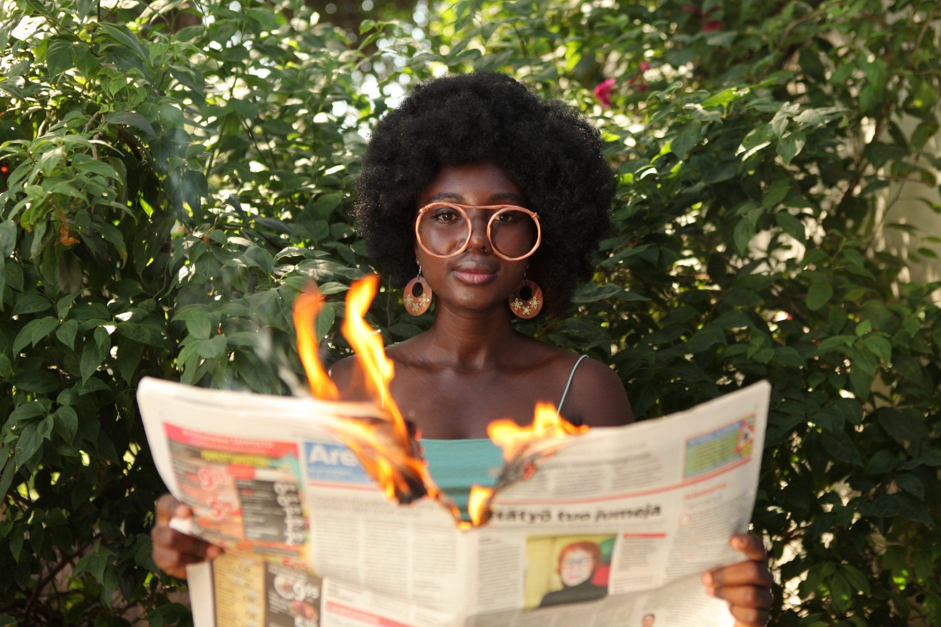 A woman is reading a newspaper with flames coming out of it.