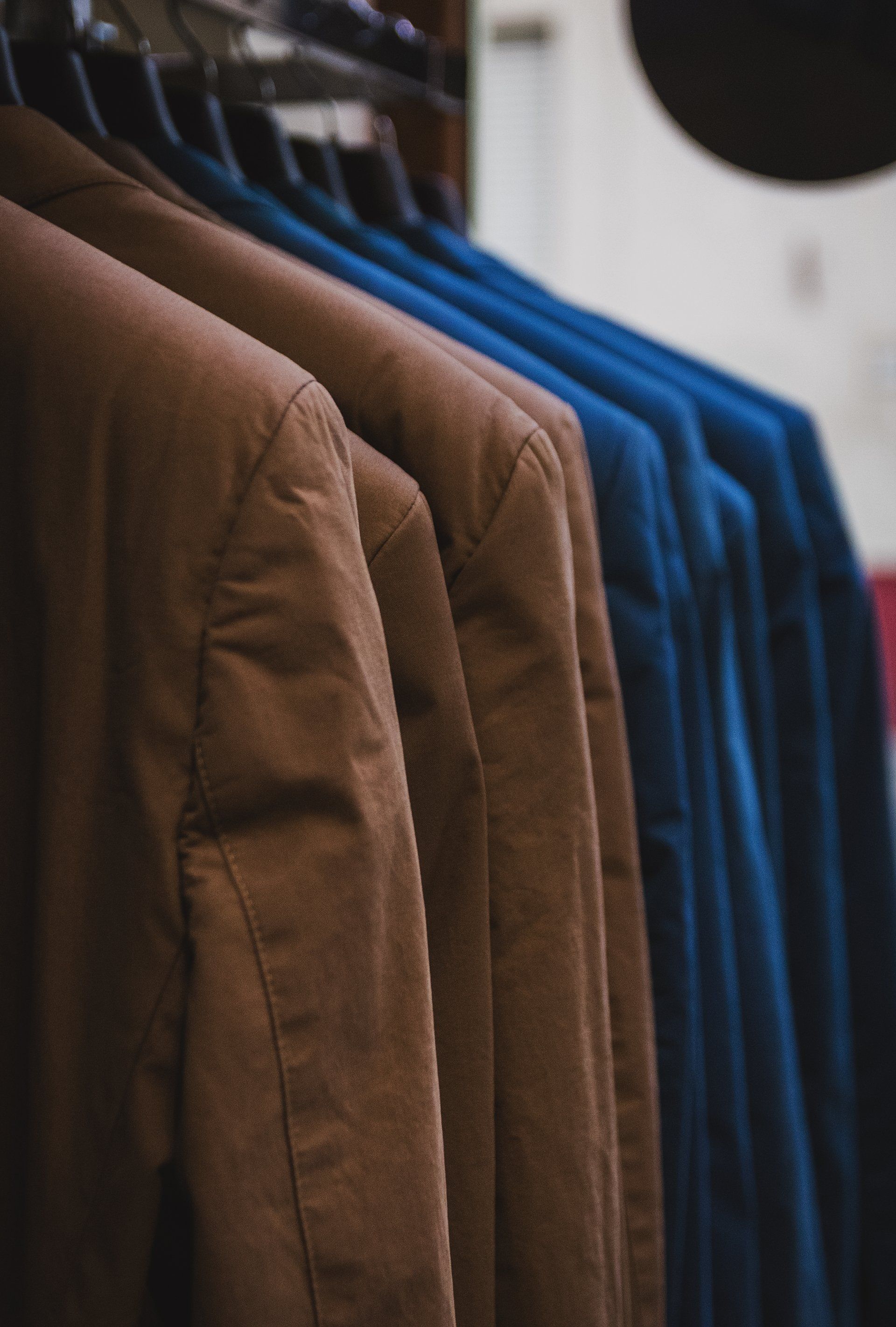 Brown and blue suit jackets hanging on a rack.