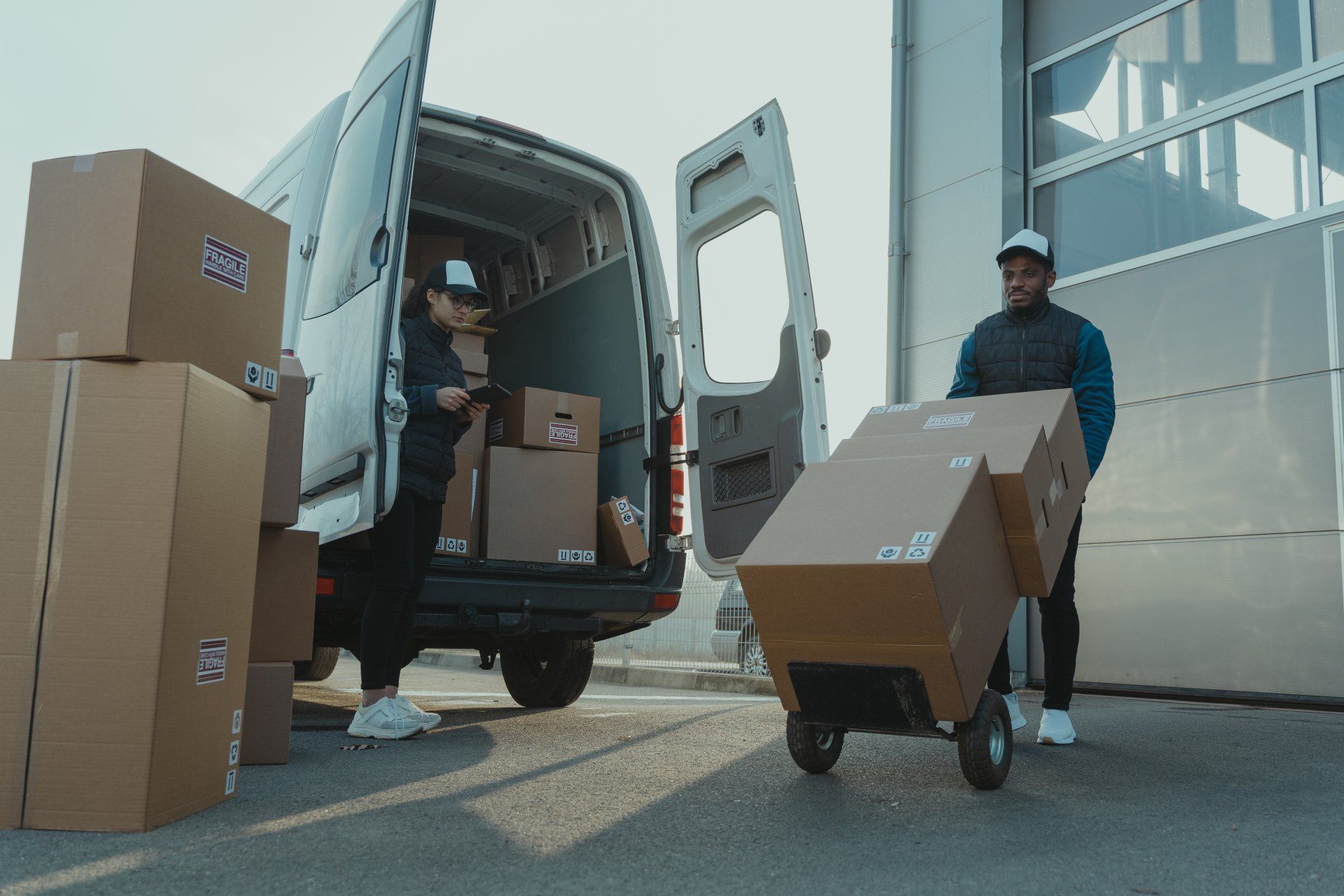 two delivery men are loading boxes into a van .
