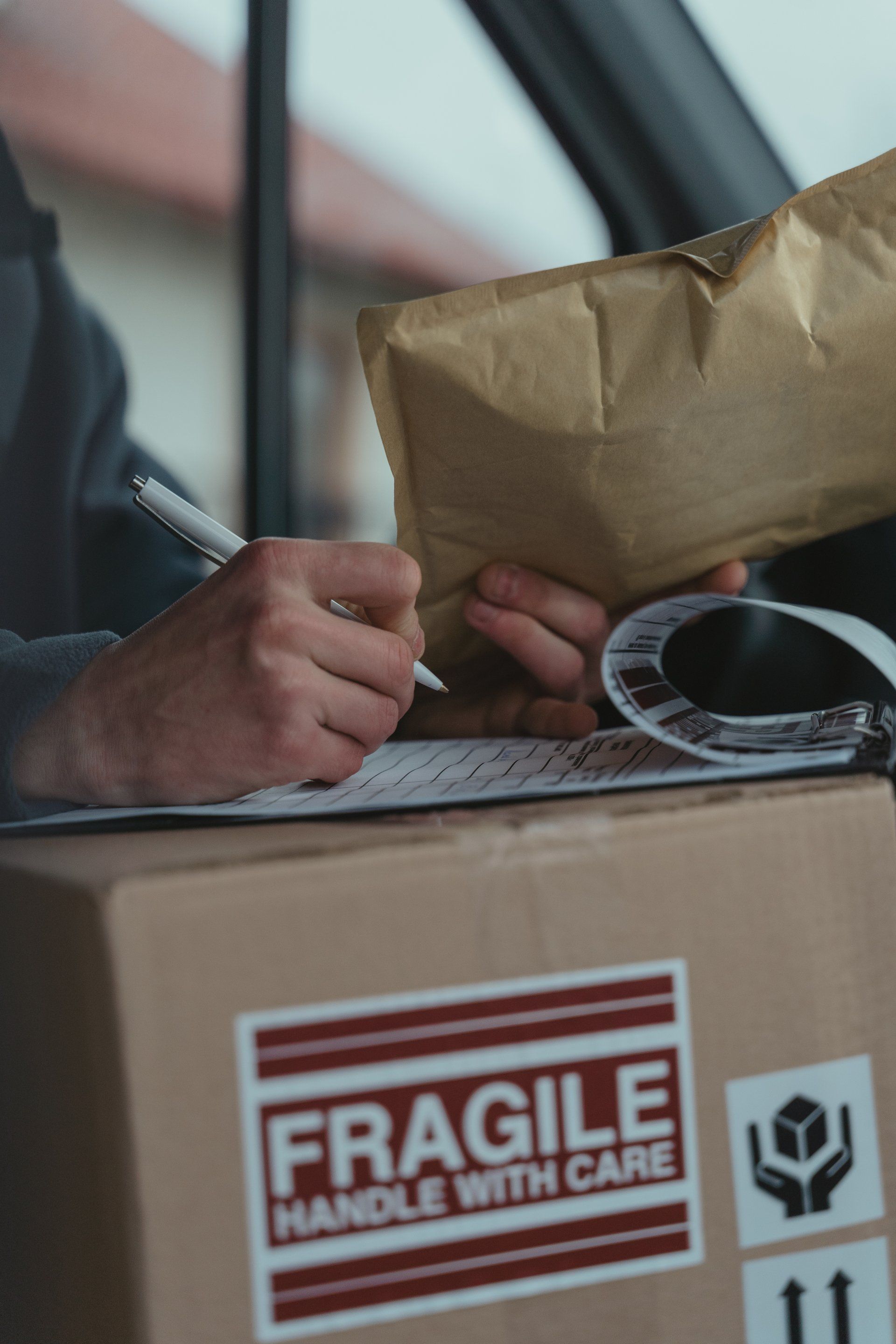 A person is writing on a piece of paper next to a box that says fragile handle with care