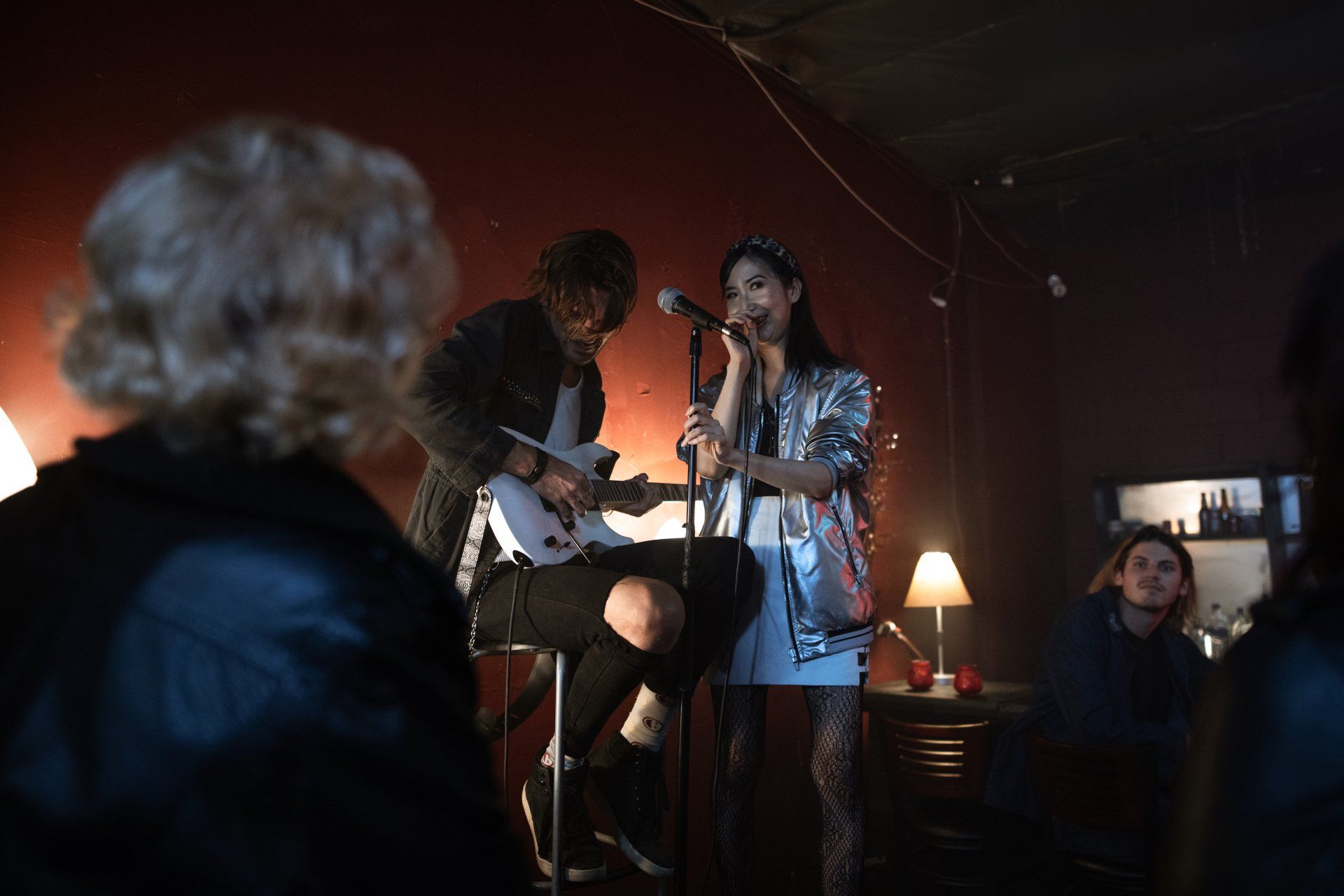 A man is playing a guitar and a woman is singing into a microphone.