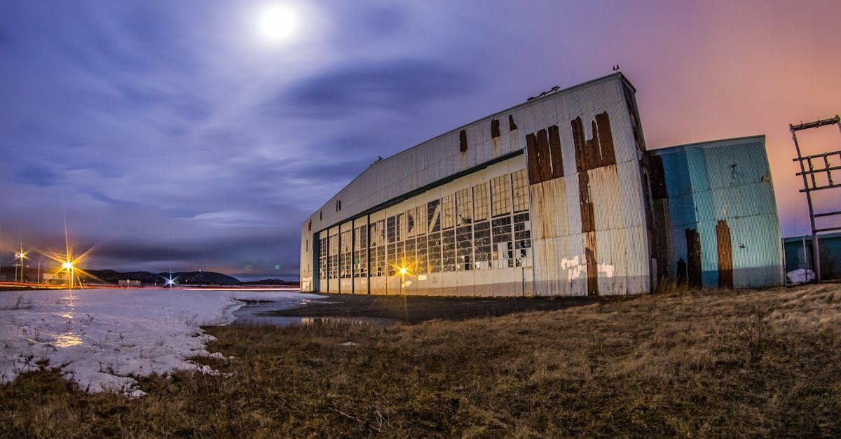 A large building is sitting in the middle of a field at night.