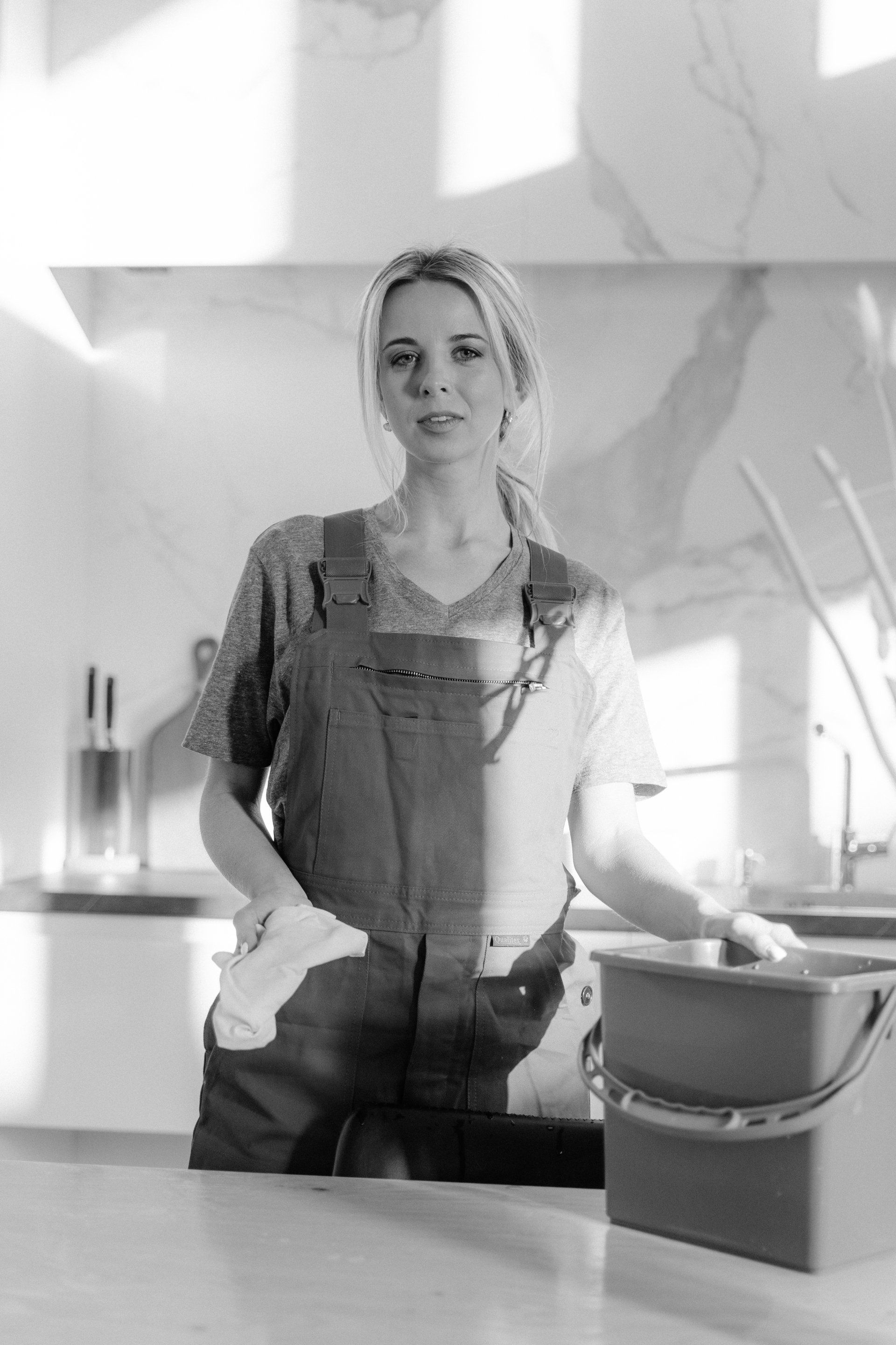 A black and white photo of a woman standing in a kitchen.
