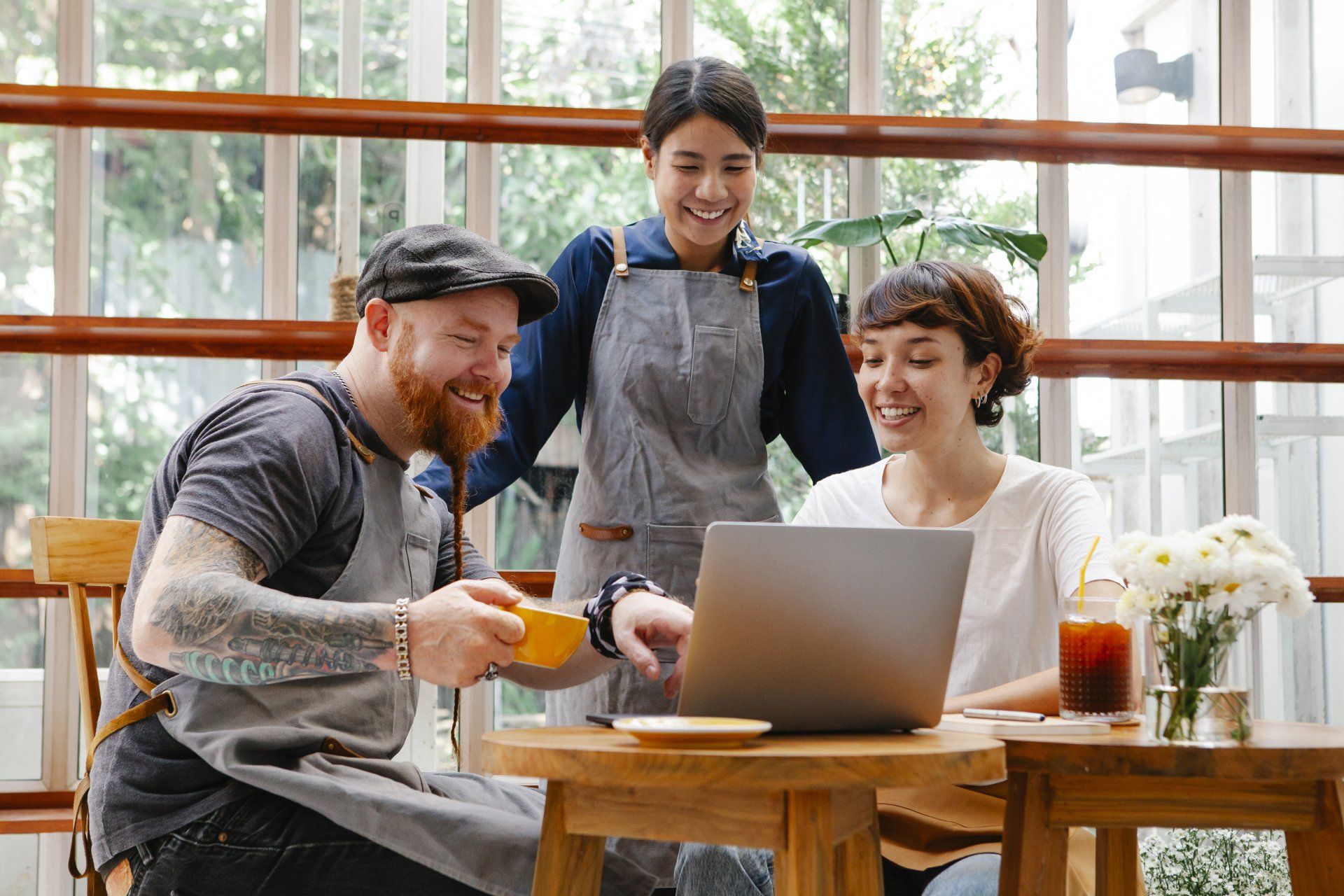 A group of people are sitting at a table looking at a laptop.