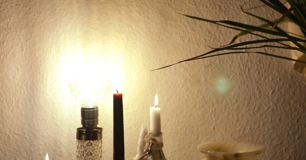 A table with candles and a lamp on it.